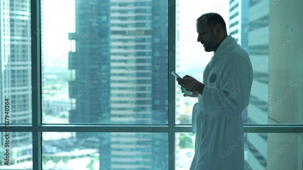 Young man in bathrobe using smartphone and drinking coffee by window at home
Young man in bathrobe using smartphone and drinking coffee by window at home
