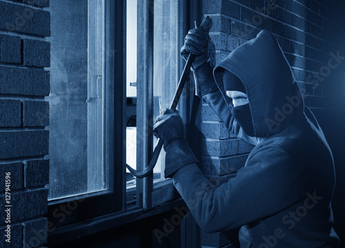 Burglar Using Crowbar To Break Into a House at night with room left and right for type