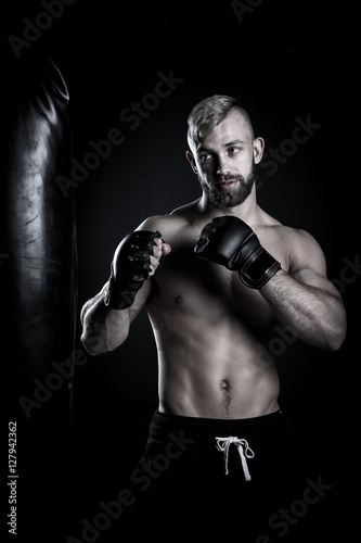 Male Athlete boxer punching a punching bag with dramatic edgy li © Dewald