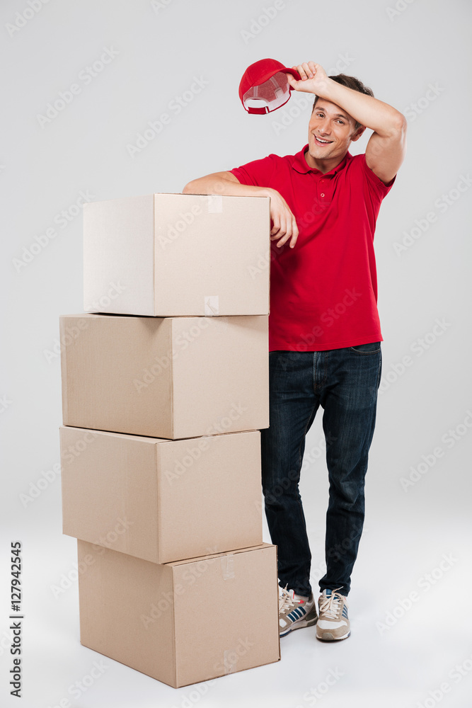 Delivery man standing in red shirt near stack of boxes