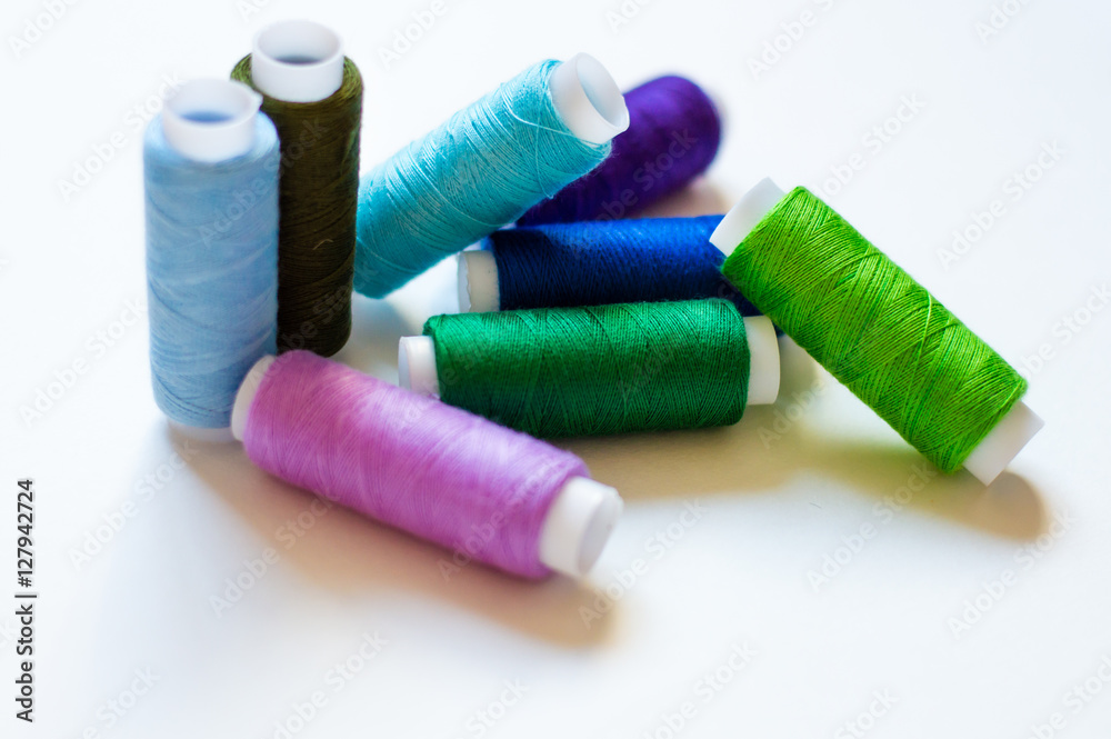 multicolored spools of thread on white background multicolored spools of thread on white background
