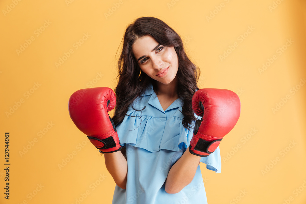 Serious young woman wearing boxing gloves and looking at camera