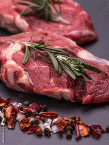 Raw beef steak with herbs and rosemary, fresh juicy on a black table background. Seleсtive focus