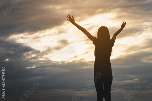 Silhouette of woman open arms under the sunrise at seaside. Silhouette of woman posing at sunset.