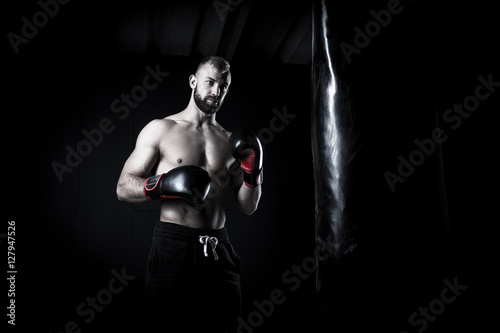 Fototapeta Naklejka Na Ścianę i Meble -  Male Athlete boxer punching a punching bag with dramatic edgy li