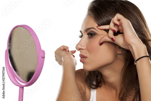 young woman looking at her wrinkles in front of the mirror
