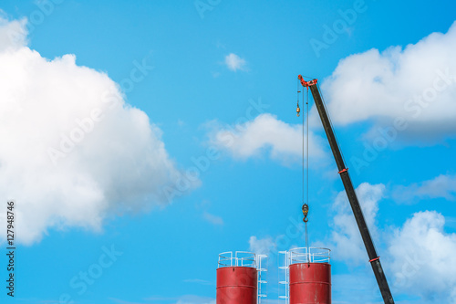 High heavy crane is working in the Cement factory construction site - hook of a crane on blue sky cloud ( Rough Terrain Crane )

 photo