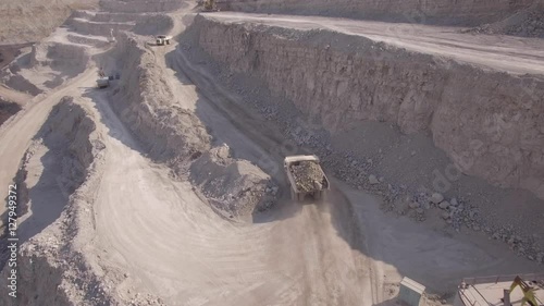Aerial view on bucket wheel excavator and big dump truck in coal mine.

