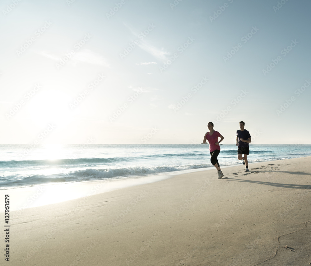 Naklejka premium Man and women running on tropical beach at sunset