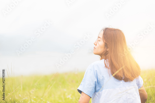 Young woman sitting at relax pose or freedom pose or chill pose on the meadow during sunrise at morning. Riverside.