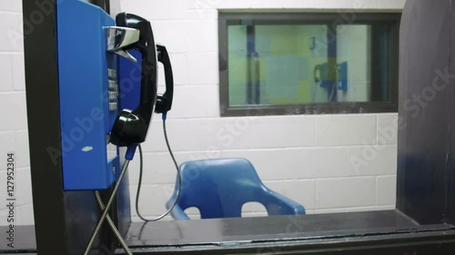 Meet area in prison jail where inmates talk on the phone with visitors behind plexiglass. Shot in 4K UHD.