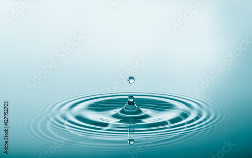 Water drop falling and drips on water mirror. Water drop splash and make perfect circles on water surface
