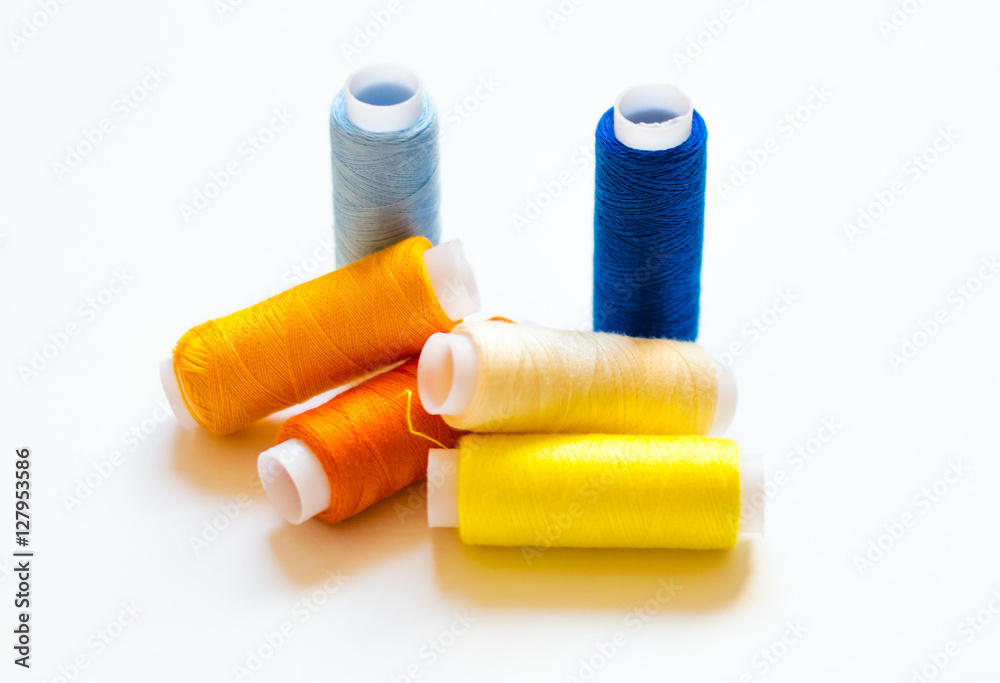 multicolored spools of thread on white background multicolored spools of thread on white background