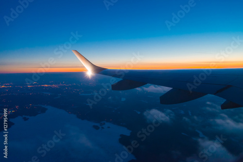 aircraft wing with light and winglet at dusk with frozen lake below 