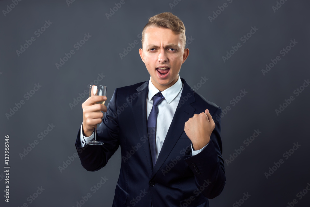 Handsome businessman holding a glass of champagne over gray background celebrating a victory, success