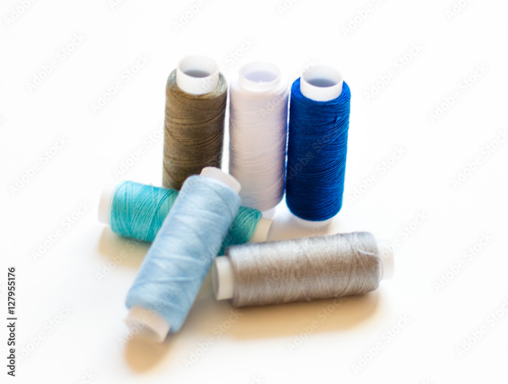 multicolored spools of thread on white background multicolored spools of thread on white background