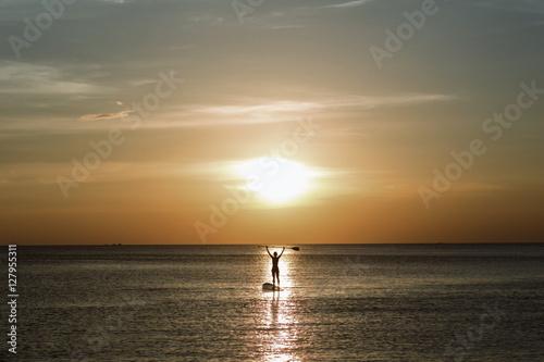 Handsome man surfing board in the tranquil sea (silhouette).