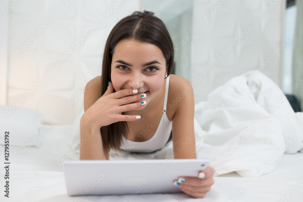 Modern woman lying in bed with her tablet PC Modern woman lying in bed with her tablet PC