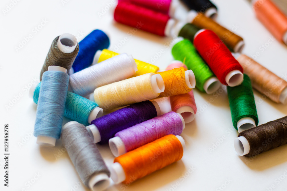 multicolored spools of thread on white background multicolored spools of thread on white background