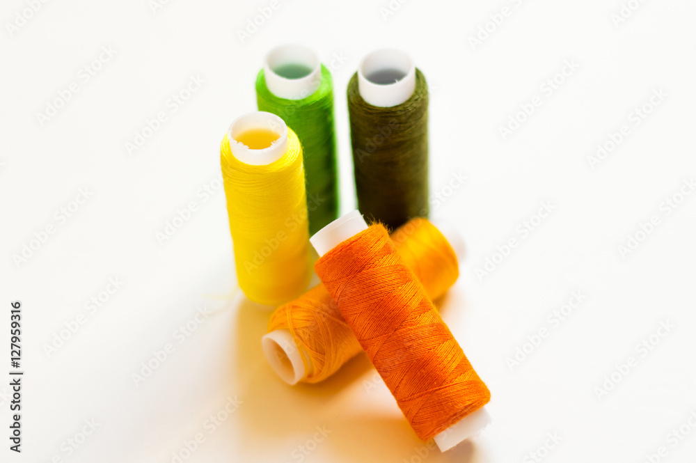 multicolored spools of thread on white background multicolored spools of thread on white background