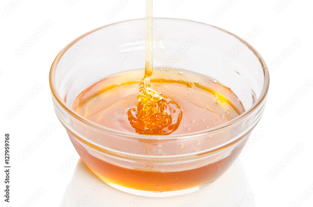 Honey dripping into glass bowl isolated on white background Honey dripping into glass bowl isolated on white background