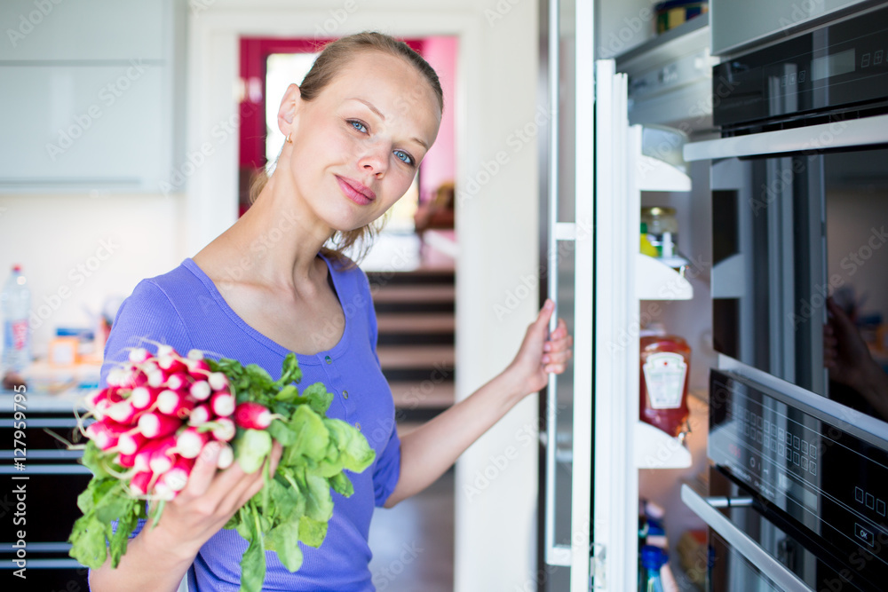 Pretty, young woman taking fresh vegetables from her fridge Pretty, young woman taking fresh vegetables from her fridge