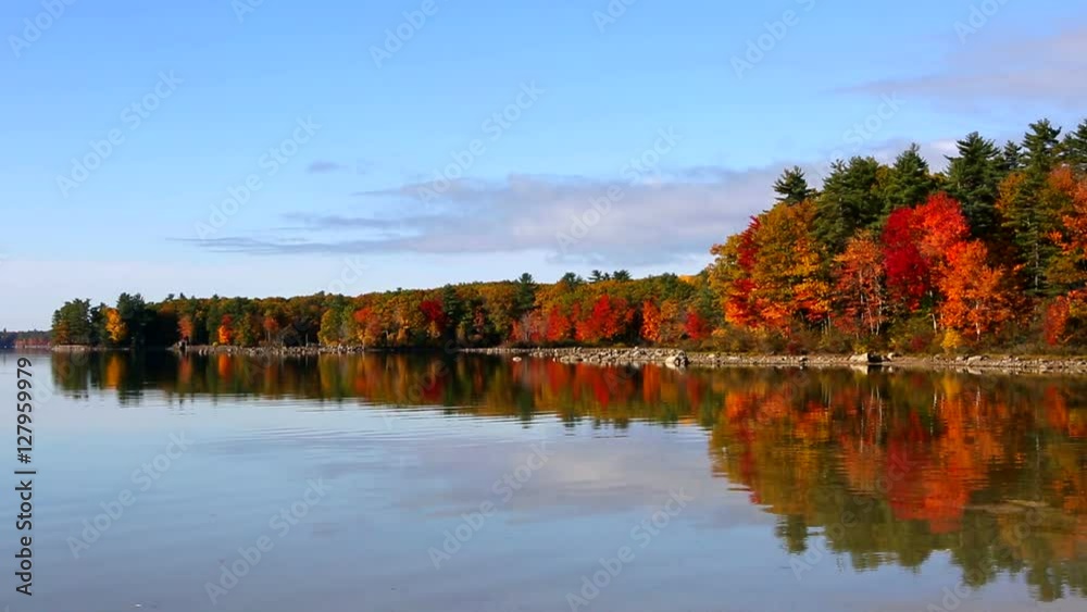Autumn fall trees reflect fall foliage colors on Lake Sabago, Maine, USA.