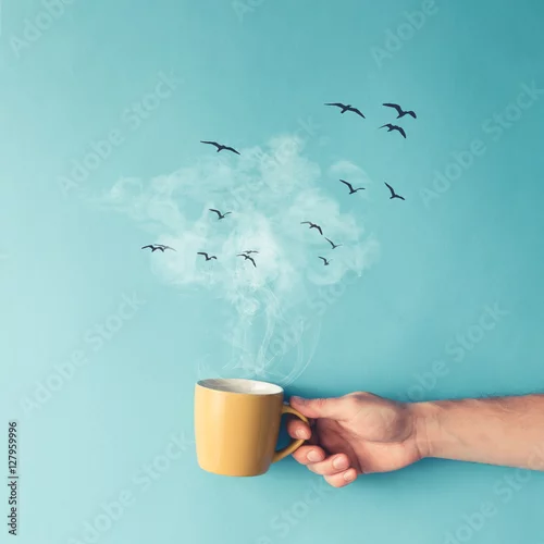 Obraz Filiżanka kawy z parą, chmurami i ptakami