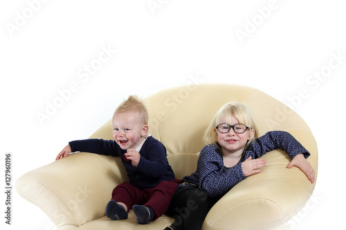 Śliczne rodzeństwo, brat i siostra bawią się na fotelu.