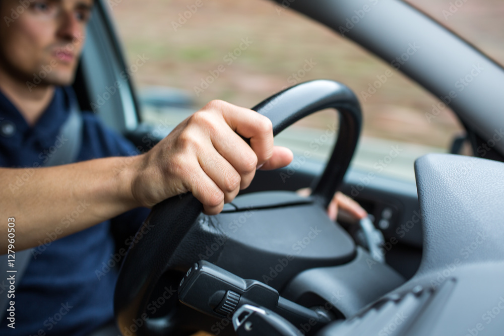 Male driver's hands driving a car on a highway 