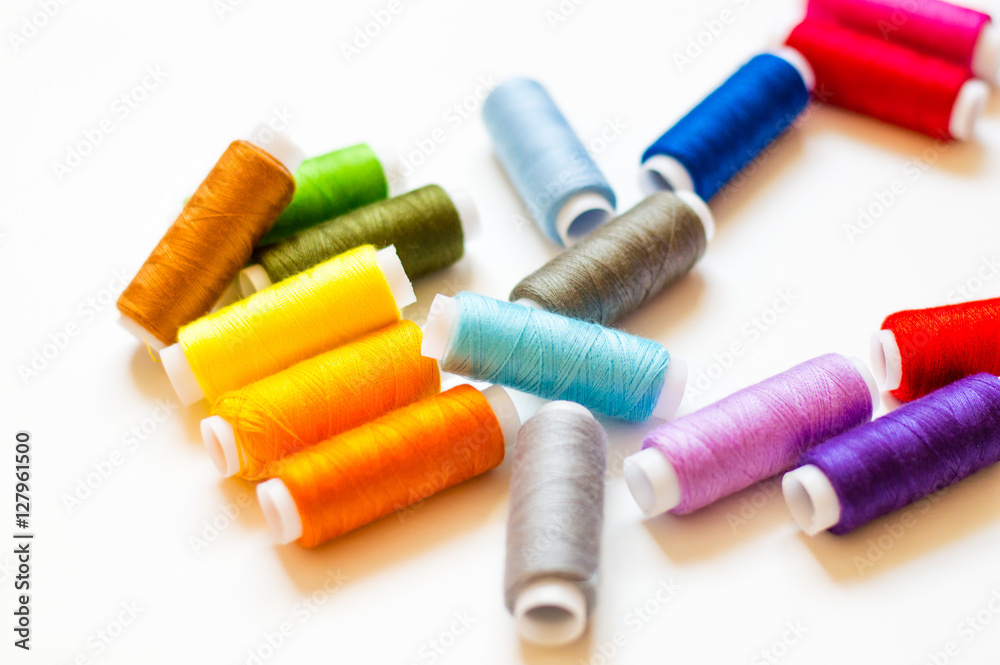 multicolored spools of thread on white background multicolored spools of thread on white background