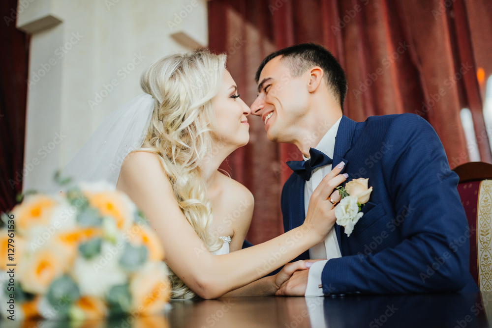 Wedding. Bride and groom smiling and looking at each other in luxury apatment. Wedding day. Bridal bouquet