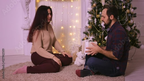 Beautiful young woman gives her boyfriend a nice gift in Christmas.