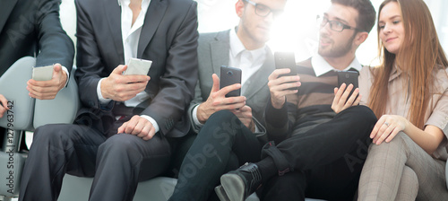 A group of young and happy young people using their phones and c