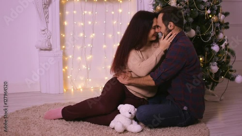 Happy couple in love at Christmas sitting before fireplace. Enjoy happy moments of his life.
