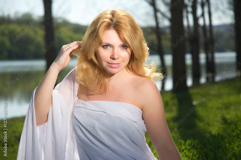 Naklejka premium Beautiful blonde girl on the river bank.