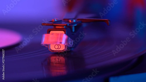 The needle drops on the disc, macro. Vinyl disc turning on retro record player.