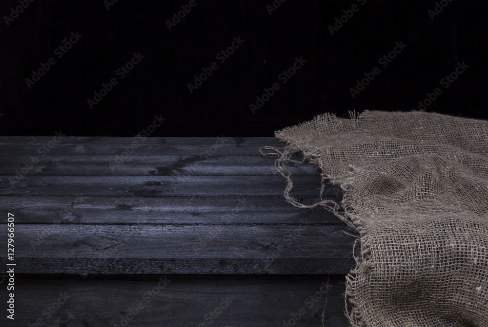 Dark wooden table with burlap for product display montage, black wooden interior Dark wooden table with burlap for product display montage, black wooden interior