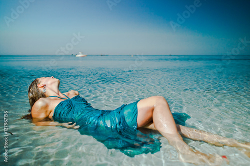 woman girl in turquoise laying in water on beach at sea ocean photo