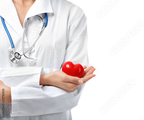 Young female cardiologist holding plastic heart on white background