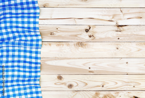 Blue checkered tablecloth on wooden table, top view
