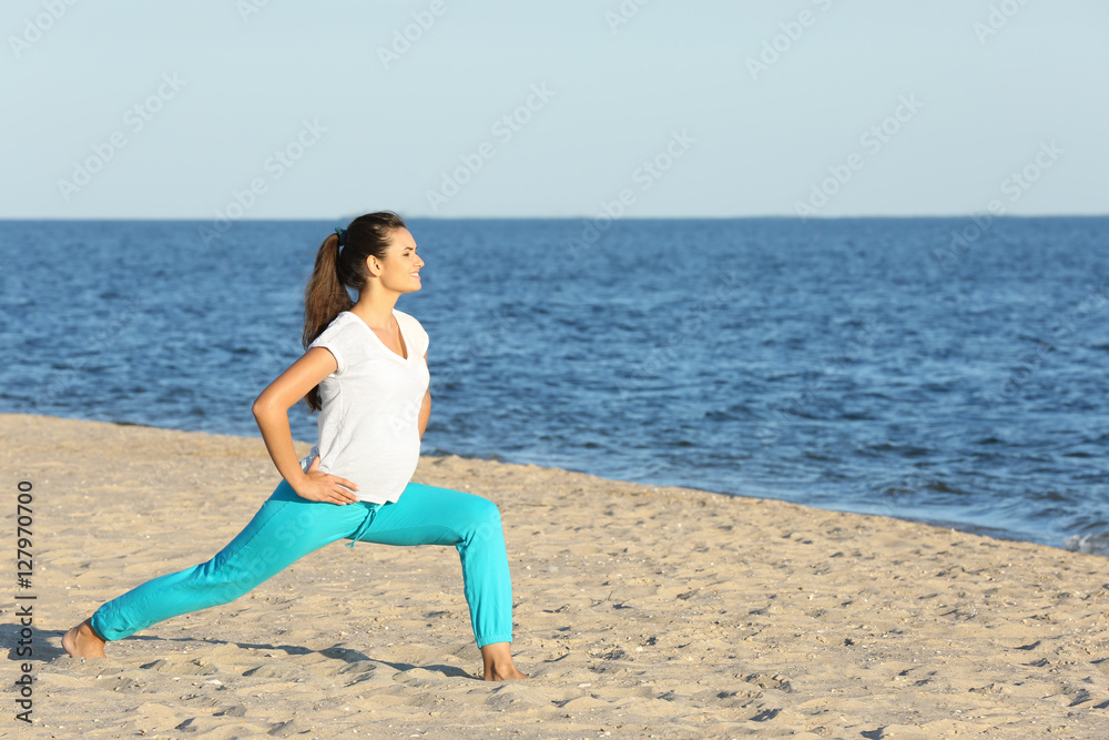 Young pregnant woman doing yoga exercises on the beach Young pregnant woman doing yoga exercises on the beach
