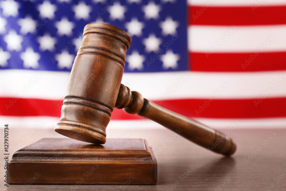 Wooden gavel on table against blurred USA flag Wooden gavel on table against blurred USA flag