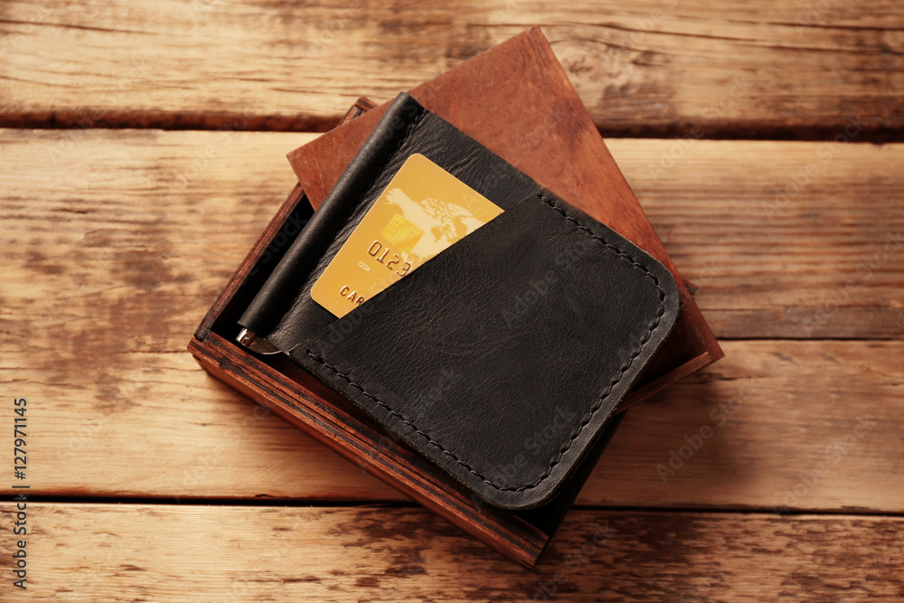Stylish leather wallet with credit card and box on wooden background