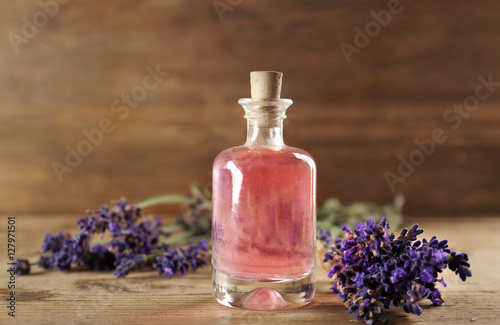 Bottle with aroma oil and lavender flowers on wooden background