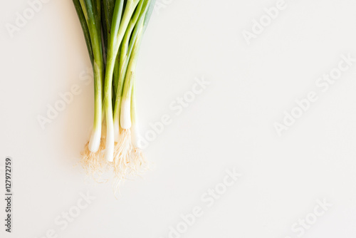Cropped view of spring onions on white table from above with copy space to right