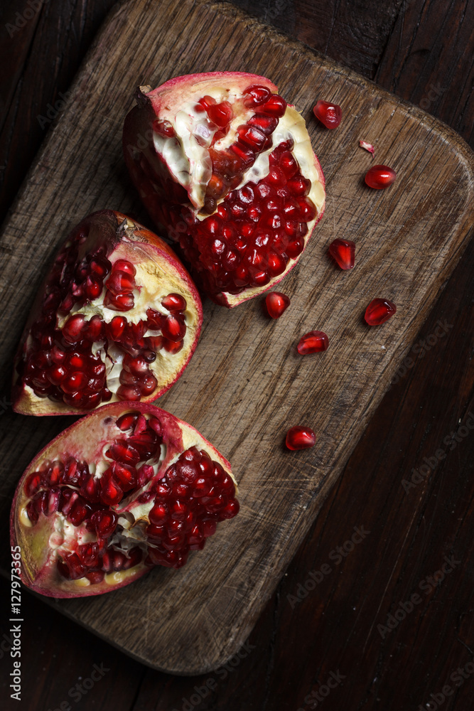 cut part of pomegranate on a wooden board on a wooden background. cut part of pomegranate on a wooden board on a wooden background.