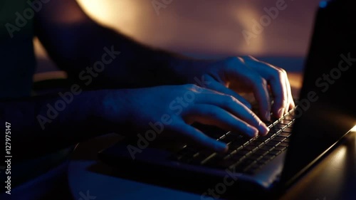 hacker at night in a dark blue illuminated office typing on a computer keyboard