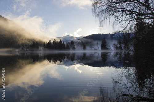 Lake Erlaufsee in Austria in Winter with fog, clouds and sun with reflection