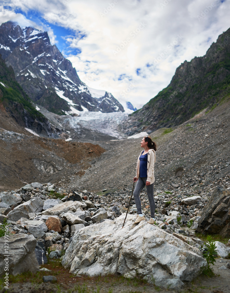 Girl in hike to the glacier, stands on a rock